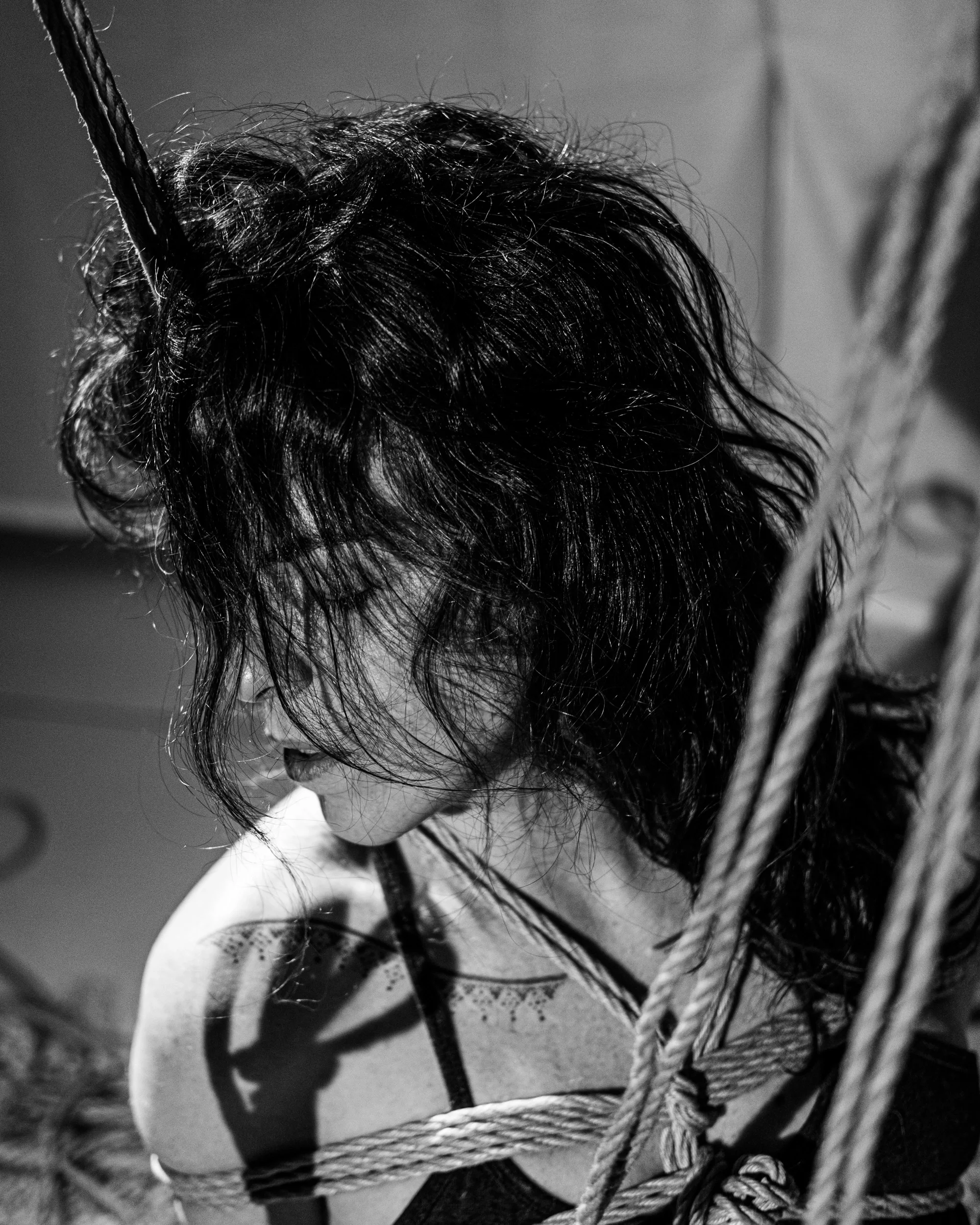 Close black-and-white portrait of hair, light and rope.
